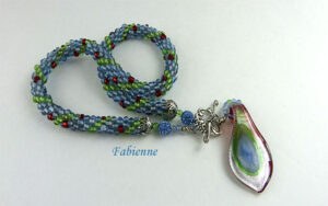 Collier de perles Fabienne est composé de Les couleurs sont bleu vert et des insertions de rouge. terminé par des embouts de métal argent une grosse perle Shambala bleu et deux petites perles et un magnifique fermoir a bascule décoratif argent. Son pendentif est en forme de larme avec des couleurs verte, bleu et rouge.Sa longueur est de 55 cm. Son pendentif est de 5 cm.www.metiersdart-cadeaux.com