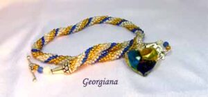 collier de perles Georgiana. Ce collier de perles a été créé avec des perles de rocaille de couleur or argent et bleue Il est terminé par des embouts de métal argent et une grosse perle transparente et une perle bleue ainsi qu'une perle or. Il a un fermoir décoratif a bascule facile a attacher. Longueur 55 cm incluant le fermoir. Le pendentif est en verre de 4 cm de long.en forme de coeur avec les couleurs or, bleu et argent.