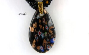 Collier de perles de verre Paula. Ce collier de perles de verre de couleur noire avec insertion de perles or est une pièce unique. Il est terminé par un embout de métal or et un fermoir a bascule or aussi.  Son pendentif est en forme de larme et il mesure 57 centimètres. Son pendentif fait 6 cms.