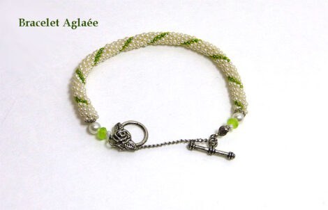 Bracelet de perles blanches avec insertion de perles vertes attache pour les personnes qui ont de la difficulté. Il y a aussi une chaine de sécurité