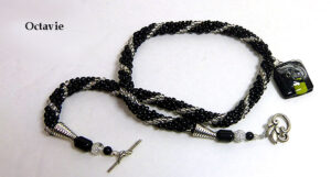 Collier de perles de verre noir avec insertion de perles blanches, ce magnifique collier de perles possède un pendentif qui est aussi en est une création unique de Mme Diane Gagné. Son fermoir est idéal pour les personnes qui ont de la difficulté avec leurs mains.