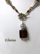 Collier de perles Elmina, Ce collier est composé de perles brunes avec insertion de perles or.Il est terminé par une cone argent et des petites perles brunes et or. Il mesure: 59cm son pendentif est carré de couleur brune et or et il mesure 6cm.. Le fermoir est a bascule en argent