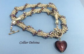 Collier de perles transparent blanc avec insertion de perles cubiques mauve terminé par un coeur mauve. Ce collier à un fermoir décoratif il facilite l'attachement au collier.