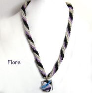 Collier de perles de verre Flore, perles transparente avec insertion de perles noires et lila. Son pendentif mesure Le collier de perles mesure 55 cm. Son pendentif 3 cm.