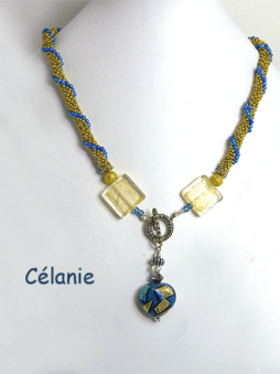 Collier crocheté de perles or avec insertion de perles bleues surélevées, terminées par une perle de forme carrée de murano terminé avec un joli coeur décoratif qui possède les mêmes couleurs que le collier et le fermoir est argent décoratif et facile a attacher.