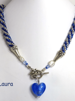 Collier de perles de rocaille fait au crochet de couleur bleue avec insertion de perles verre transparent, Il est terminé avec un fermoir décoratif et facile pour attacher le collier. Joint a ce fermoir il y a un petit coeur bleu qui termine avec élégance ce dernier