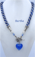 Collier de perles de verre bleu avec insertion  de  perles argent, terminé par es embouts une autre perle blanche et des embouts de métal argent et un fermoir décoratif a bascule. Dans le centre il a un pendentif en forme de coeur bleu