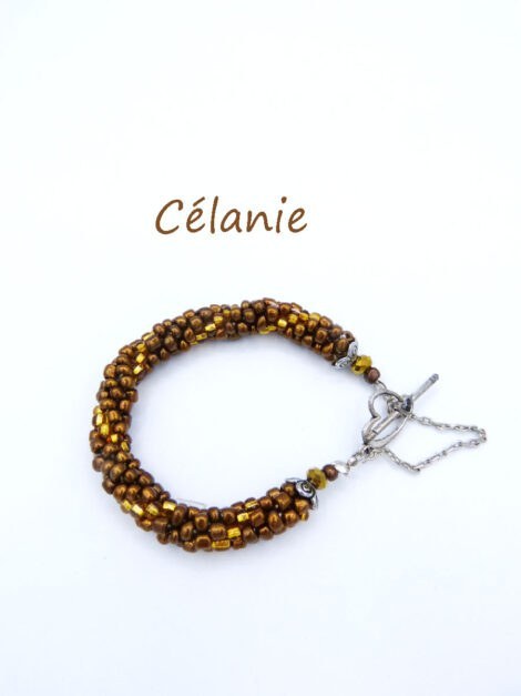 Bracelet en perles de verre Célanie il est composé de perles brune avec insertion de perles de verre de couleur or. Terminé par des embouts de méta; et une perle or et une brune. Il a un fermoir a bascule en forme de coeur et a une chaine de sécurité