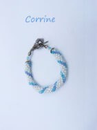 Bracelet de perles blanches avec insertion de perles bleues le tout terminé avec un embout de métal argent et un fermoir a bascule le tout terminé par une chaine de sécurité il mesure Il mesure 15 cm.r