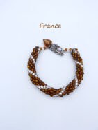 bracelet de perles France est fait de perles de verre brune avec insertion de perles de verre transparentes , fini avec un embout de métal argent et de petites perles brunes et blanches et un petit coeur en verre brun le tout terminé par un fermoir a bascule Ce bracelet est de15 cm de longueur. Il est fait de perles de rocaille.