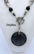 Collier de perles Delphine, il est composé de perles noire avec insertion de perles argent et or le tout est terminé par des embouts de métal argent et une grosse perle noire et une autre plus petite. Il possède un fermoir a bascule qui est très décoratif. Son pendentif est une pièce de céramique noire avec insertion de petits points blanc.Il mesure 61 cm de long est facile à utiliser avec fermoir décoratif argenté. Son pendentif est en céramique il fait 5 cm.