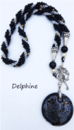 Collier de perles Delphine, il est composé de perles noire avec insertion de perles argent et or le tout est terminé par des embouts de métal argent et une grosse perle noire et une autre plus petite. Il possède un fermoir a bascule qui est très décoratif. Son pendentif est une pièce de céramique  noire avec insertion de petits points blanc.