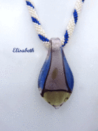 collier de perles Elisabeth. Collier de perles Élisabeth, il a été créé avec des perles de blanche avec insertion de perles bleues. Le fermoir à bascule est très décoratif est bien pour les personnes qui ont des douleurs aux mains. Il mesure 46 cm pendentif  est en forme de larme avec les couleurs de bleue lilas, jaune  et une ligne de noire il mesure 6cm