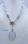 Collier de perles blanches avec insertion de perles bleues le tout terminé par un cone en argent et une petite perle blanche et une bleue. Le fermoir est a bascule argent et son pendentif mesure Fermoir pour les personnes qui ont des douleurs aux mains. Sa longueur est de 47 cm Le pendentif est de 4 cm la longueur du collier est de 47 cm