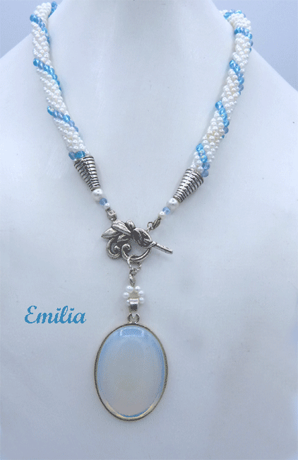 Collier de perles blanches avec insertion de perles bleues le tout terminé par un cone en argent et une petite perle blanche et une bleue. Le fermoir est a bascule argent et son pandent