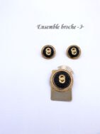 Ensemble broche et boucles d'oreilles. La broche est or et rectangulaire avec un cercle or et insertion d'une perle noire la broche mesure 3,5cm x5,5cm et les boucles d'oeilles sont pour les oreilles percées.