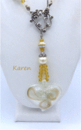 collier de perles blanches avec insertion de perles or, il est terminé par un embout de métal en argent, une grosse perle et deux petites perles son fermoir est décoratif et a bascule. il a un pendentif en forme de coeur blanc avec des insertions de couleur or. Sa taille est de 60 cm incluant le fermoir Le pendentif en verre mesure 4 1/2 cm long
