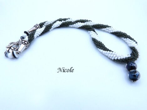 Collier de perles de verre fait au crochet. Les perles sont noires avec insertion de perles blanches le tout terminée par un fermoir à bascule argent et le pendentif est deux grosses perles en verre transparent et noir.