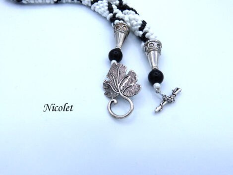 Collier de perles Nicolet il est composé de perles blanches avec insertion de perles noires en diagonales Il a un fermoir a bascule argent Il mesure 50 cm le pendentif 6 cm. Un diamètre de 3 1/2 cm