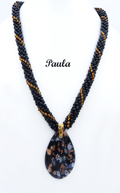 Ce collier de perles de verre de couleur noire avec insertion de perles or. Il mesure 57 centimètres Son pendentif fait 6 centimètres.