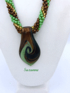 Le collier Suzanne de notre collection Métiers d’Art et Cadeaux est définitivement le nouveau favori. Ce collier est en plus passe-partout et fait avec un magnifique mélange de perles de couleurs vertes, brunes et or. Ce collier est parfait pour porter avec une tenue contractée ou sport fermoir pour personnes qui ont des douleurs aux mains. Mesure (59cm). Le pendent en verre mesure 6cm ce dernier vient avec son certificat d’authenticité.