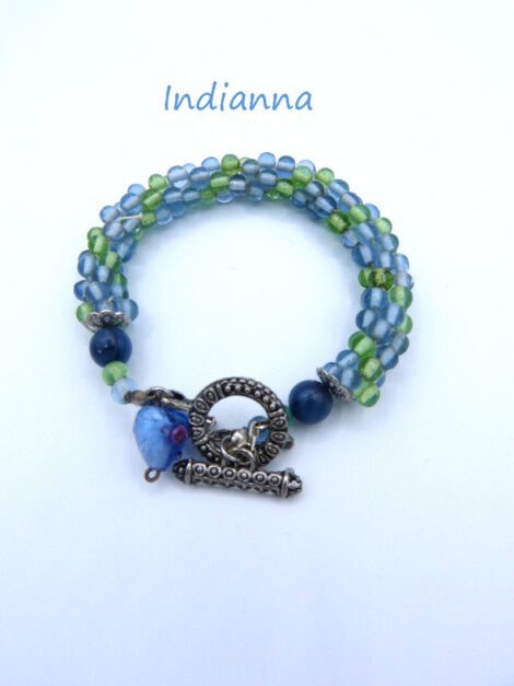 Bracelet Indiana fait avec des perles de verre bleues avec insertion de perles verte le tout terminé par un embout de métal argent et une grosse perle bleu et des petites perles verte et une perle de verre en forme de coeur. Le tout terminé par un fermoir a bascule avec une chaine de sécurité Longueur du bracelet de perles 21 cm