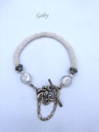 Bracelet de perles Gaby il est composé de perles de verre blanc et transparent il est terminé par des embouts de métal argent et une petite perle blanche et une grosse perle transparente. Il possède un fermoir a bascule avec une petite chaîne de sécurité. Il mesure 21 à 25cm.