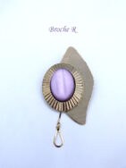 Broche la pierre est de couleur mauve et est sur un oval ciselé en argent et le tout sur une autre base en forme de larme argent uni. Le tout terminé avec une petite chaine décorative mesure 6 X 3 cm