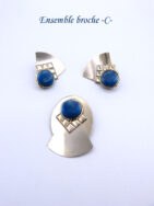 Cette broche est un bijoux mode entièrement fait à la main elle est ovale avec insertion d'un carré le tout surmonté d'une perle bleue elle mesure 6 cm X 3cm. Les boucles pour les oreilles sont avec des pinces avec coussinets .mesurent 4,cm