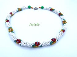 Collier de perles blanches avec des perles rouge, jaune et vert qui forme des fleurs sur le collier il est terminé par des embouts de étal argent , une grosse perle blanche et une grosse perle verte et deux petites perles or et rouge. Son fermoir décoratif est à bascule en argent. Il mesure 57 cm