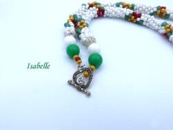 Collier de perles blanches avec des perles rouge, jaune et vert qui forme des fleurs sur le collier il est terminé par des embouts de étal argent , une grosse perle blanche et une grosse perle verte et deux petites perles or et rouge. Son fermoir décoratif est à bascule en argent. Il mesure 57 cm