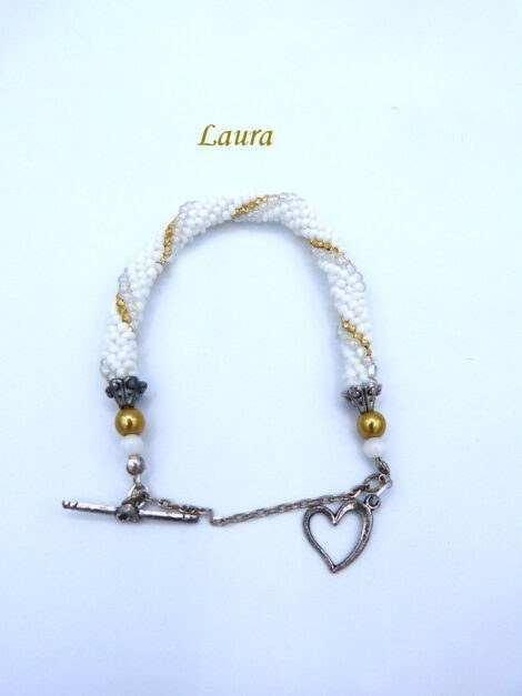 Magnifique bracelet de perle Laura Il est composé de petites perles blanches avec insertion de perles or et de perles transparentes. le tout terminé par des embouts de métal argent et une grosse perle or et une autre blanche. Il a un fermoir à bacul en forme de coeur et une chaînette de sécurité. Il mesure 17 cm