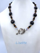 Collier de perles Lisette est composé de grosses perles noires avec des plus petites et des perles brunes et deux petites perles transparentes et un fermoir a bascule facile pour attacher. Modèle : Lisette Fermoir qui est aussi décoratif. Dimension: 49 cm.