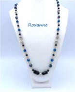 collier de perles Roxanne. Il est composé dans le centre de deux perles noires rectangulaires et par la suite de belles perles bleues et de perles noire et argent. Fermoir qui est aussi décoratif. Dimension: 78 cm.