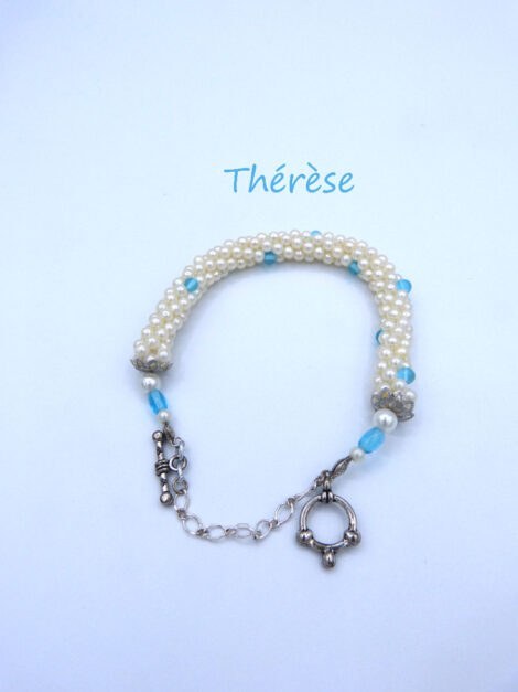 Ce bracelet de perles blanches avec de petites insertions de perle bleue, il est terminé par un embout en métal argent une plus grosse perle blanche et une grosse perle bleue et une petite perle blanche. Il est terminé par un fermoir a bascule avec une chaîne de sécurité. Il mesure 18 cm.