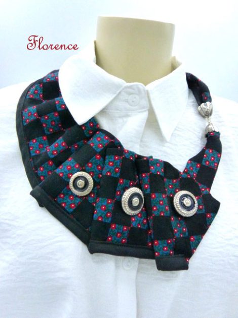 collier fait avec une cravate de couleur noire avec un peu de bleue et des petits points rouges a aussi trois boutons.
