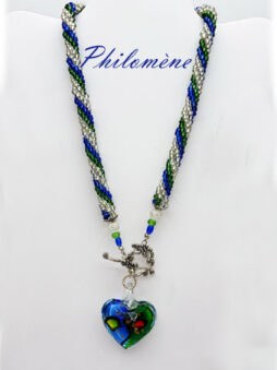 Cette pièce maîtresse, transparente et cristalline, est agrémentée de perles de verre reflétant la lumière à chaque mouvement. Ce collier est plus qu’un simple accessoire ; c’est un symbole de raffinement. Les touches de couleur vert et bleu, apportent une histoire de mer et de ciel, de profondeur et de sérénité.
