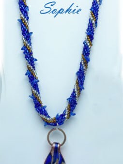 Je suis ravie de vous présenter ce magnifique collier perlé de couleur bleue, agrémenté de perles de verre transparentes et brunes. Son pendentif en verre apporte une touche classique et chic à son design coloré et disc